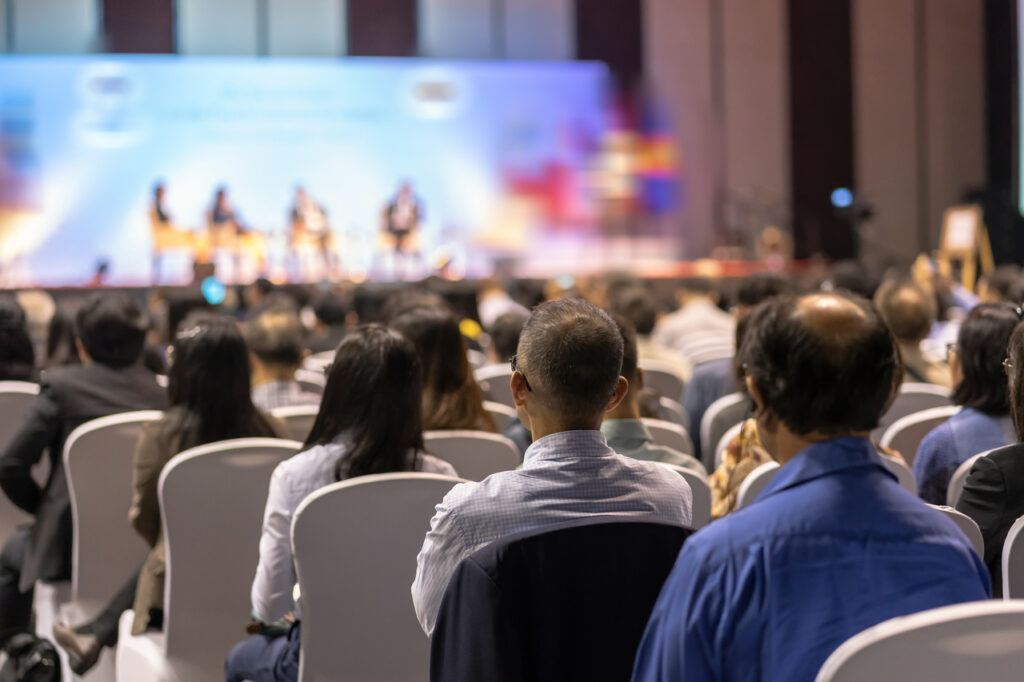 rear view of audience listening speakers on the stage in the con